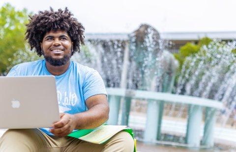 student sitting at the base of the lion fountain smiling